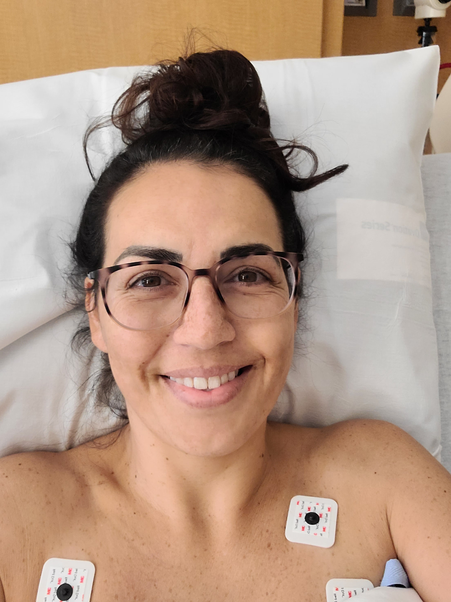 Toni resting in a hospital bed hooked up to monitors